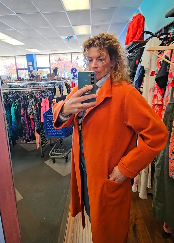 Juliet d'Epagnier trying on a secondhand coat at a thrift store